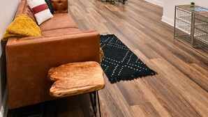 Un soggiorno moderno con un divano in pelle marrone, un tavolo da pranzo con sedie e un tappeto nero.