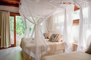 Un dormitorio con cama con dosel, vistas al verdor exterior y una hamaca.