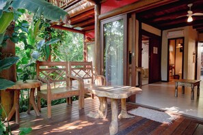 A wooden deck with a table and chairs, surrounded by lush greenery. - Solar Pitanga - Taipu de Fora (Maraú)