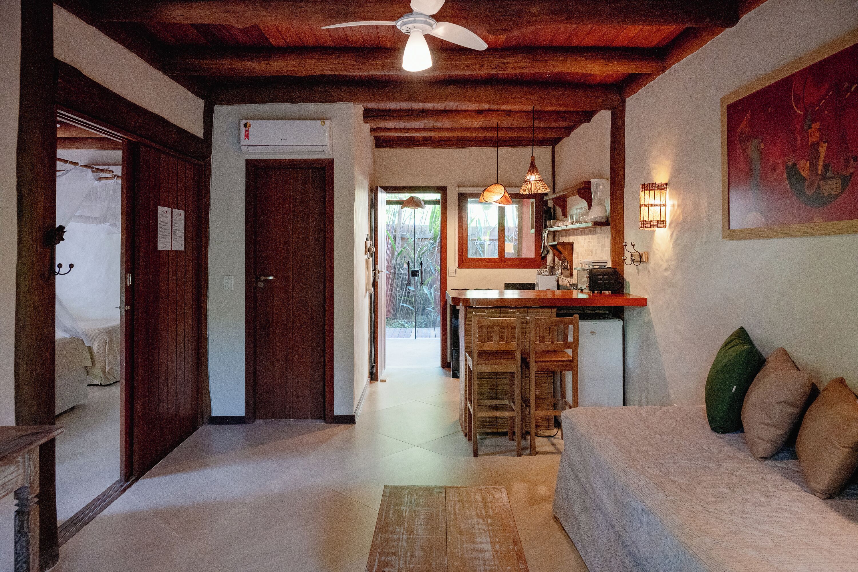 A living room with a sofa, a wooden coffee table, and a kitchen area with a bar and counter.