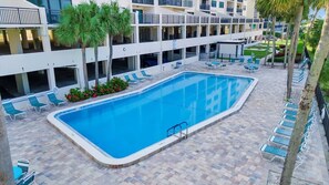 A rectangular pool with a tiled deck, surrounded by lounge chairs and palm trees. - Million Dollar Gulf View-2 Bed 2 Bath (Clearwater)