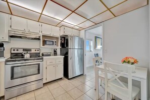 A modern kitchen with stainless steel appliances, white cabinetry, and a tiled floor. - Million Dollar Gulf View-2 Bed 2 Bath (Clearwater)