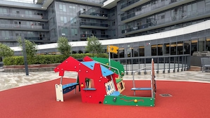 A playground with a red surface and colorful play structures.