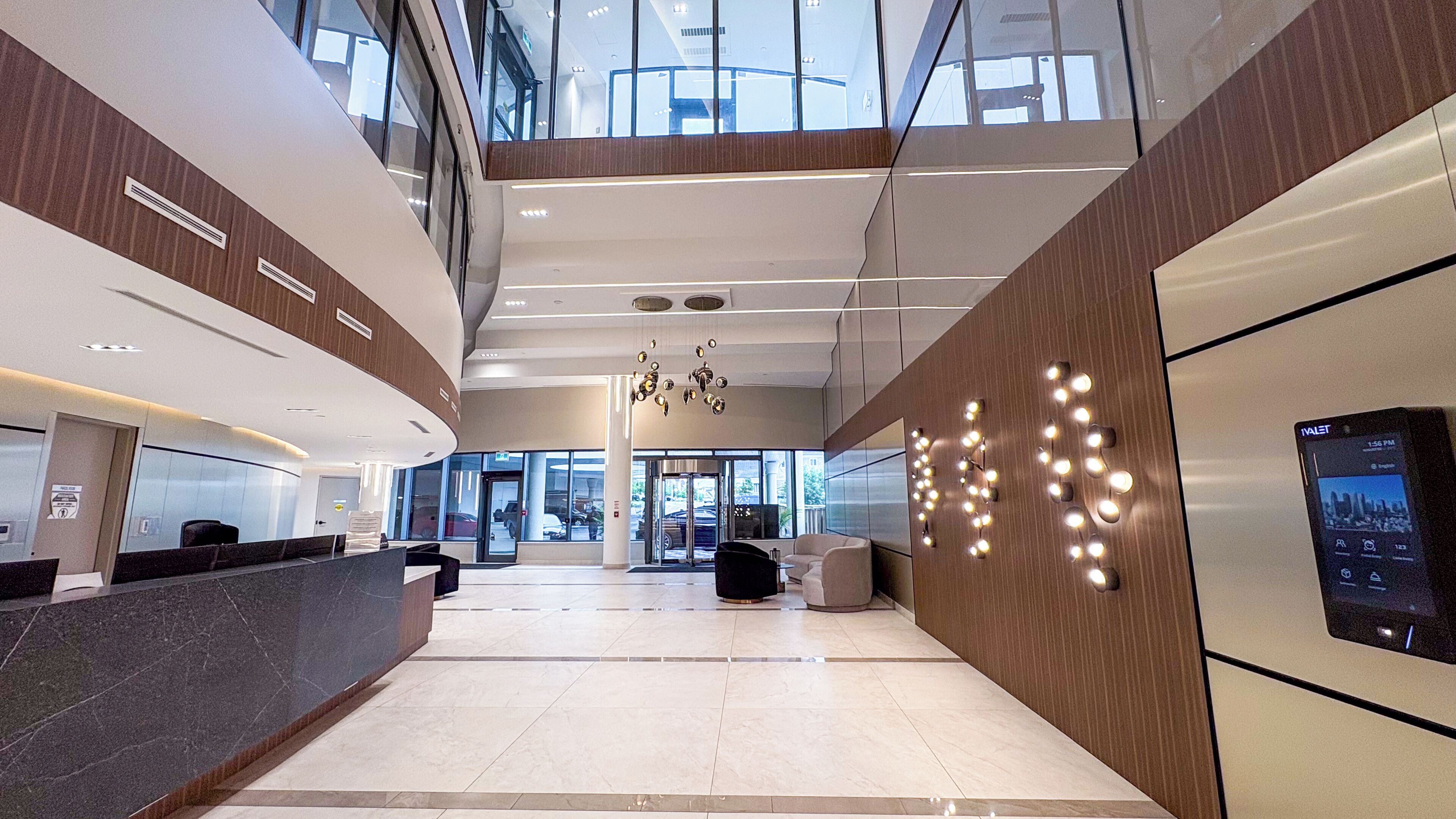 A modern hotel lobby with a reception desk, seating area, and a large digital display.
