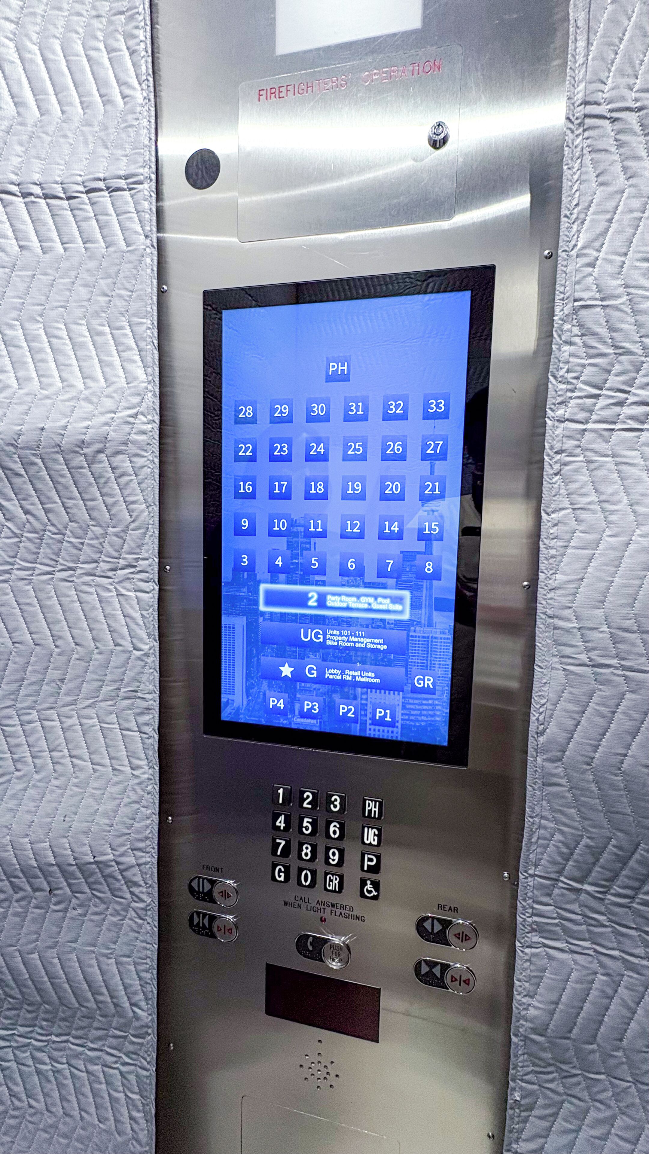 A digital elevator control panel with a keypad and a screen displaying floor numbers.