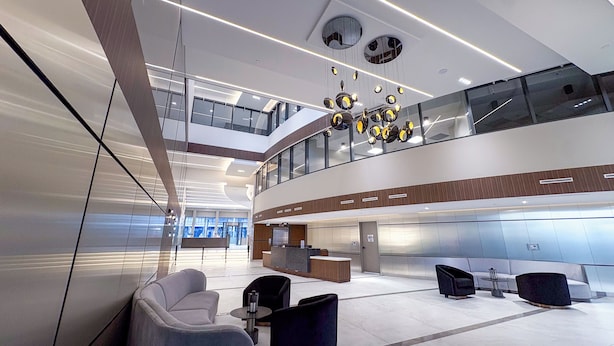 A modern lobby with a reception desk, seating area, and a staircase leading to an upper level.