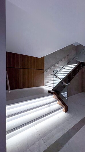 Una escalera moderna con barandas de vidrio e iluminación integrada.