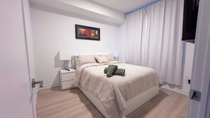 Ein Schlafzimmer mit einem Bett, einem Nachttisch, einer Lampe und einem Bild an der Wand.
