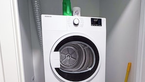 A compact, two-door washing machine in a small utility room.