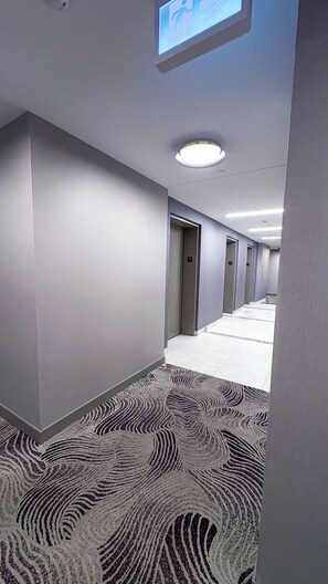 Ein Hotelgang mit einem gemusterten Teppich, nummerierten Türen, darunter Nummer 31, und einer Deckenleuchte.