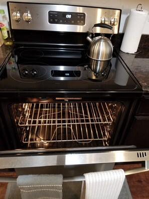 A stainless steel oven with a digital display, a kettle, and a roll of paper towels on the countertop. - Spacious 4-bedroom house in lovely Fort Worth. Quiet neighborhood, pet friendly. (Fort Worth)