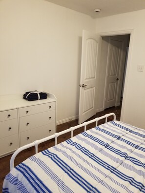 Ein Schlafzimmer mit einem Bett, einem Schminktisch und einer Tür zu einem anderen Raum.