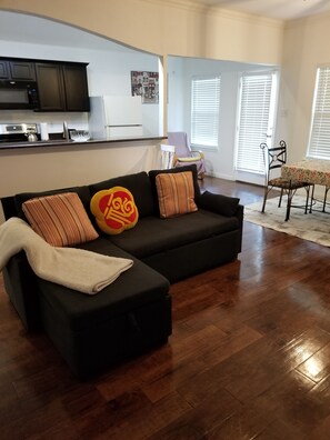 A living room with a black sectional sofa, a kitchen area with a microwave, and a dining area with a table and chairs. - Spacious 4-bedroom house in lovely Fort Worth. Quiet neighborhood, pet friendly. (Fort Worth)