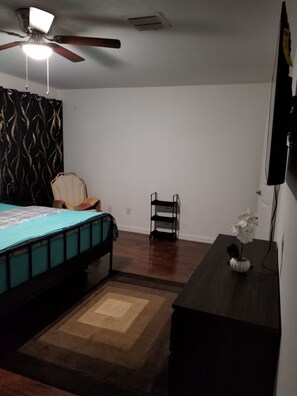 A bedroom with a bed, a ceiling fan, a small table with a vase, and a chair. - Spacious 4-bedroom house in lovely Fort Worth. Quiet neighborhood, pet friendly. (Fort Worth)