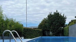 A clear blue swimming pool with metal ladders on one side, surrounded by greenery and a hedge. - Mandrati Loft Room 06 | Sea View Balcony, Heated Pool & Breakfast (Sarpi)