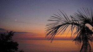 A sunset over a calm sea with a palm tree silhouette. - Mandrati Loft Room 06 | Sea View Balcony, Heated Pool & Breakfast (Sarpi)