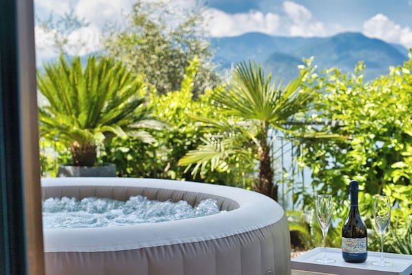 A hot tub surrounded by lush greenery and a mountain view.