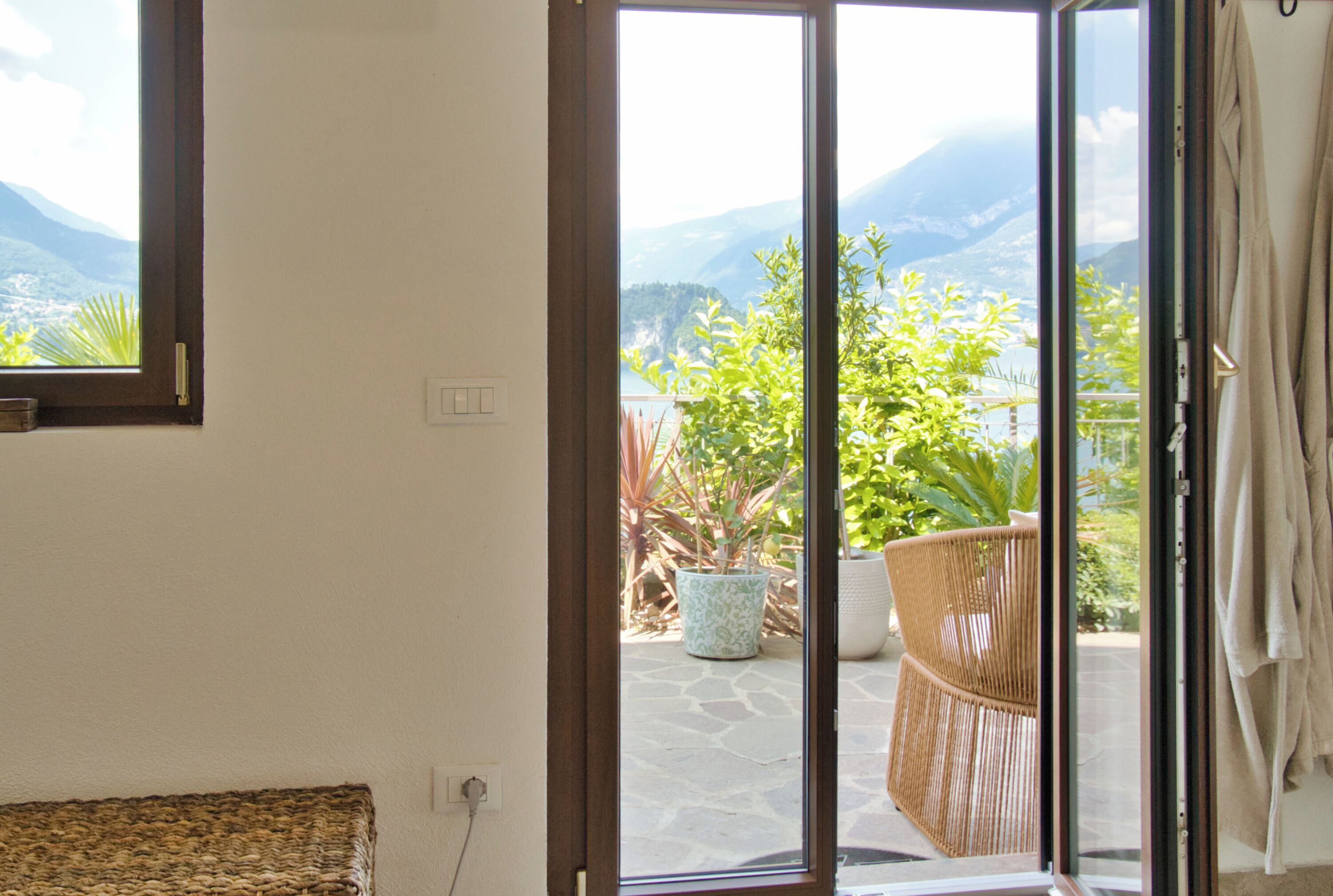 Una habitación con puerta corrediza de vidrio que da a un espacio exterior con vistas a montañas y vegetación.