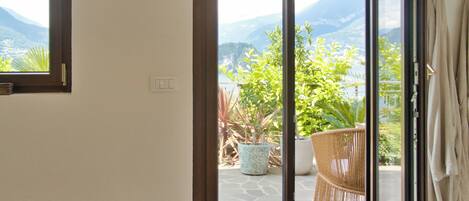 Una habitación con puerta corrediza de vidrio que da a un espacio exterior con vistas a montañas y vegetación.
