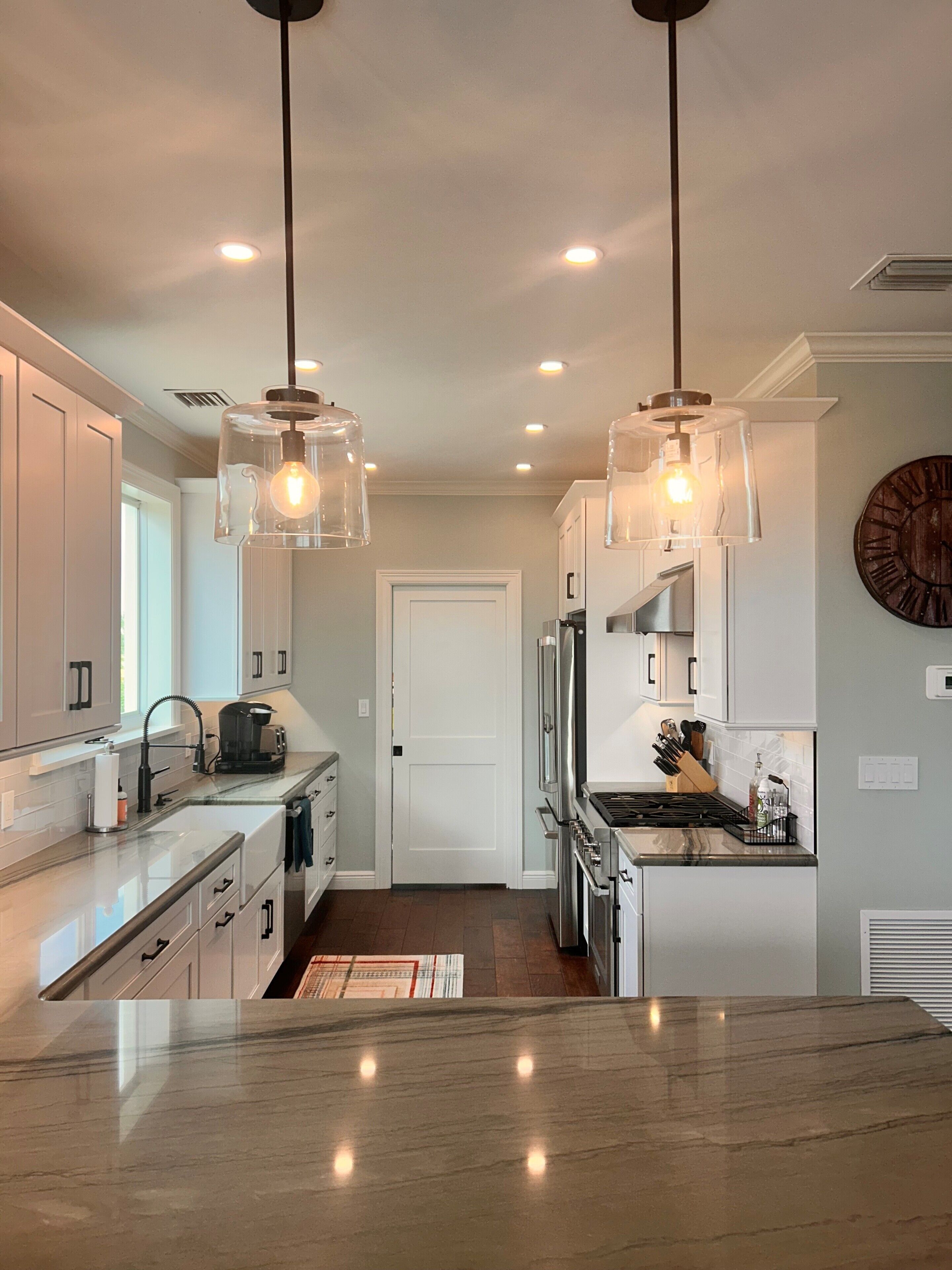 A modern kitchen with pendant lighting, stainless steel appliances, and a marble countertop.