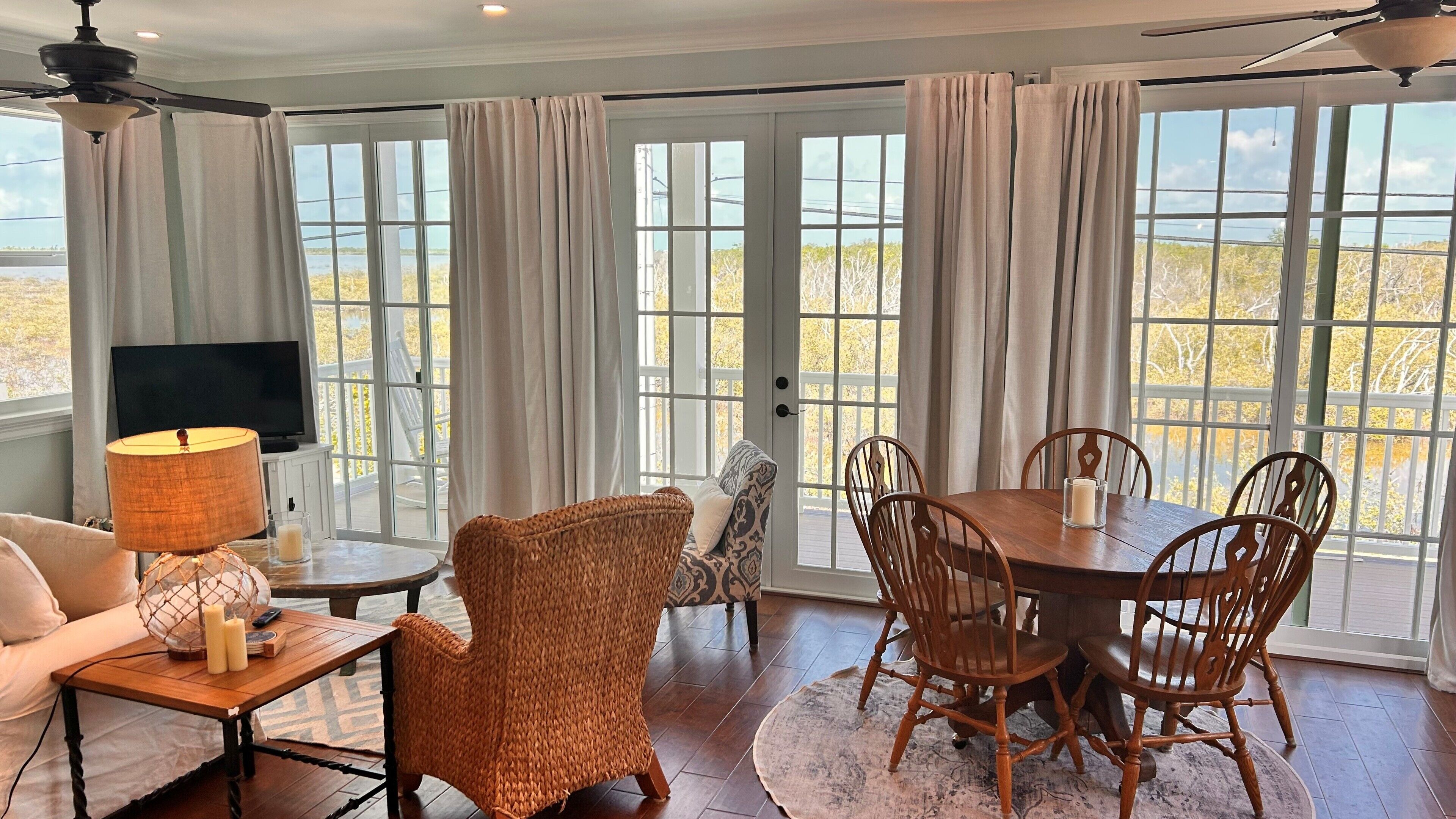 A room with a dining table, chairs, a television, and a sofa.