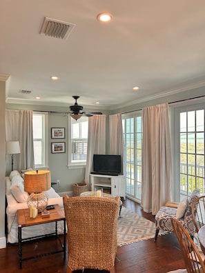 A living room with a sofa, a coffee table, a TV on a stand, and a ceiling fan. - New 4 bed 3 bath house on Ramrod Key (Ramrod Key)