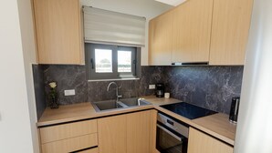 A modern kitchen with wooden cabinets, a built-in oven, a sink, and a window with blinds.