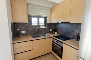 A modern kitchen with wooden cabinets, a built-in oven, a sink, and a window with blinds.