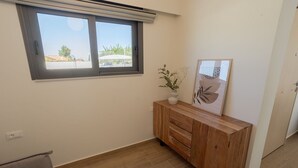 A room with a window, a wooden cabinet, a plant, and a framed artwork.
