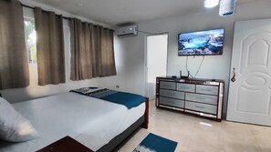 A bedroom with a bed, a dresser, a television, and a door. - Vista Marina Beach (Playa Juan Dolio)