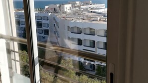 Une vue depuis un balcon, avec un ciel dégagé, donnant sur une zone côtière avec des bâtiments et un complexe hôtelier.