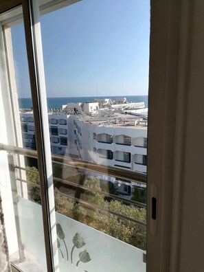 Blick von einem Balkon bei blauem Himmel auf eine Küstenlandschaft mit Gebäuden und einem Kurort.