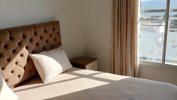 Une chambre d’hôtel avec un grand lit, une table de chevet et une vue sur la mer.
