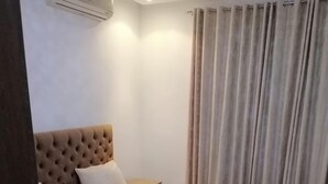 Une chambre d’hôtel avec un grand lit, une table de chevet, un appareil de climatisation et un rideau.