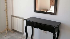 Une pièce comprenant une console noire, un radiateur et un porte-manteau en bois.