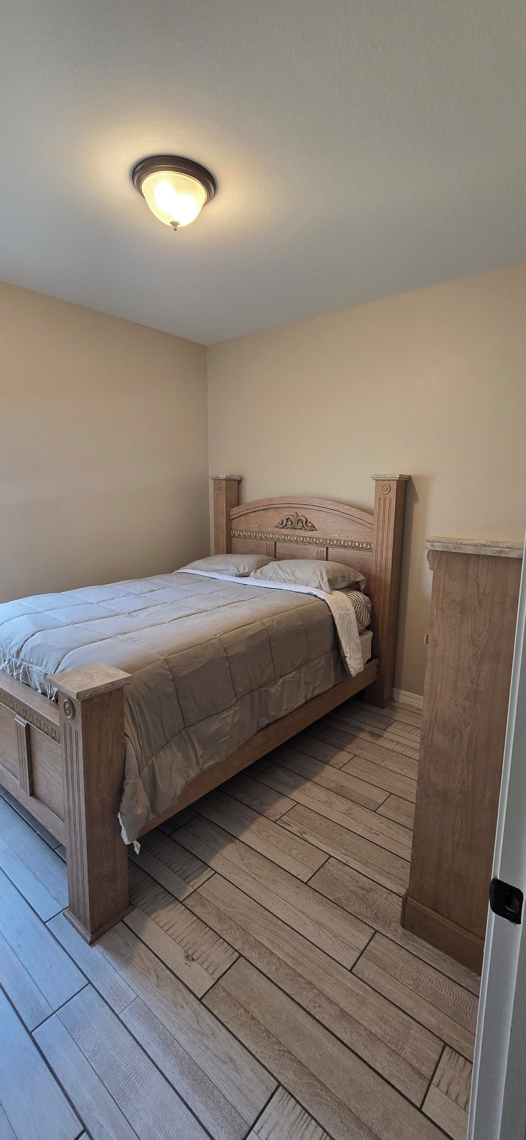 A bedroom with a wooden bed, a nightstand, and a wardrobe.