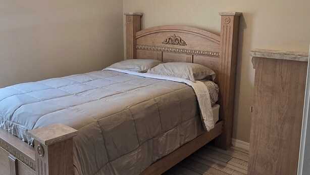 A bedroom with a wooden bed, a nightstand, and a wardrobe.