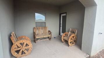 Une véranda couverte avec deux chaises en bois et une grande roue en bois.