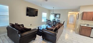 A living room with a sofa set, a coffee table, and a flat-screen TV mounted on the wall.