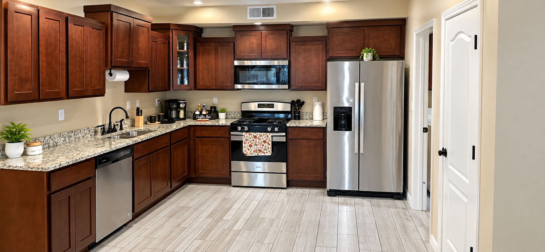 A kitchen with wooden cabinets, stainless steel appliances, a granite countertop, and a tiled floor.