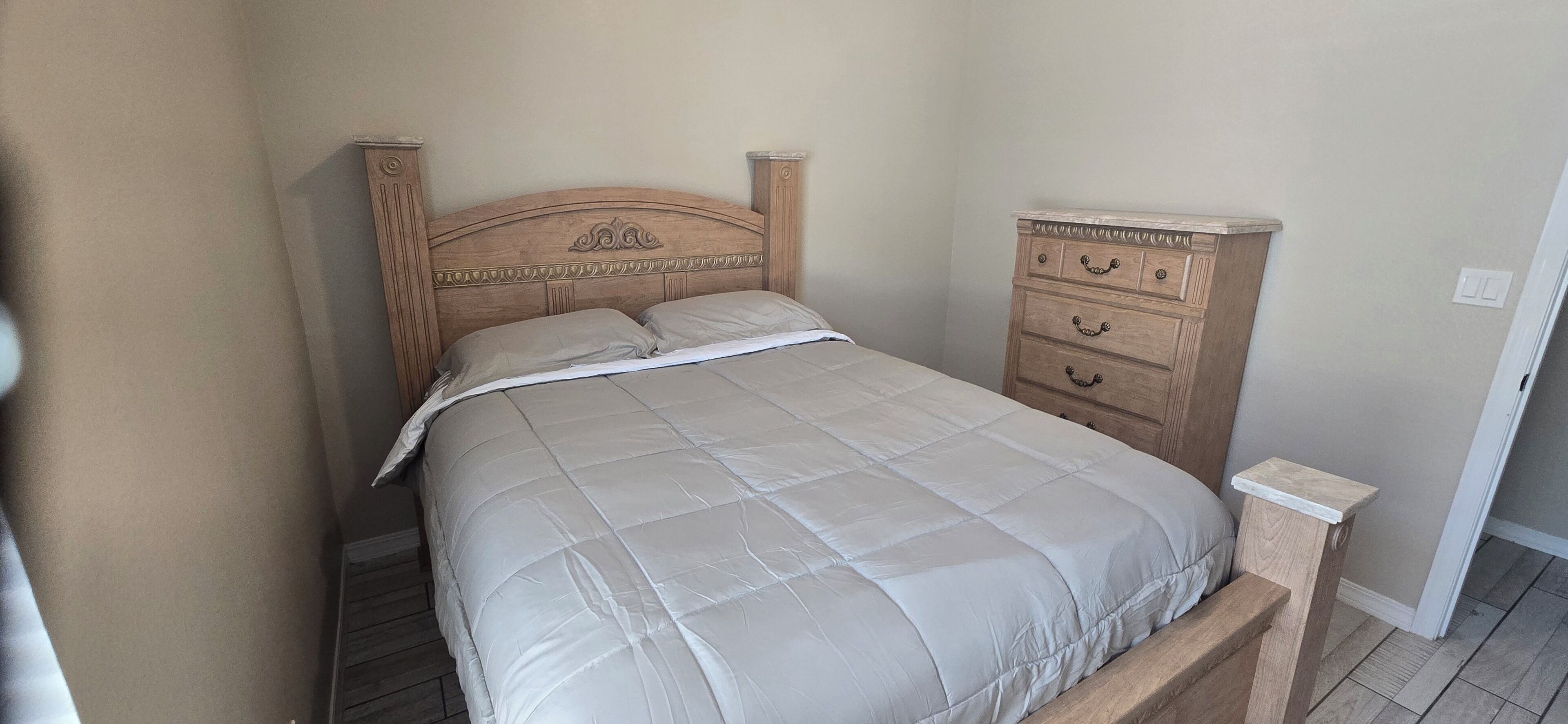 A bedroom with a bed, a wooden dresser, and a nightstand.