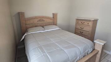A bedroom with a bed, a wooden dresser, and a nightstand.