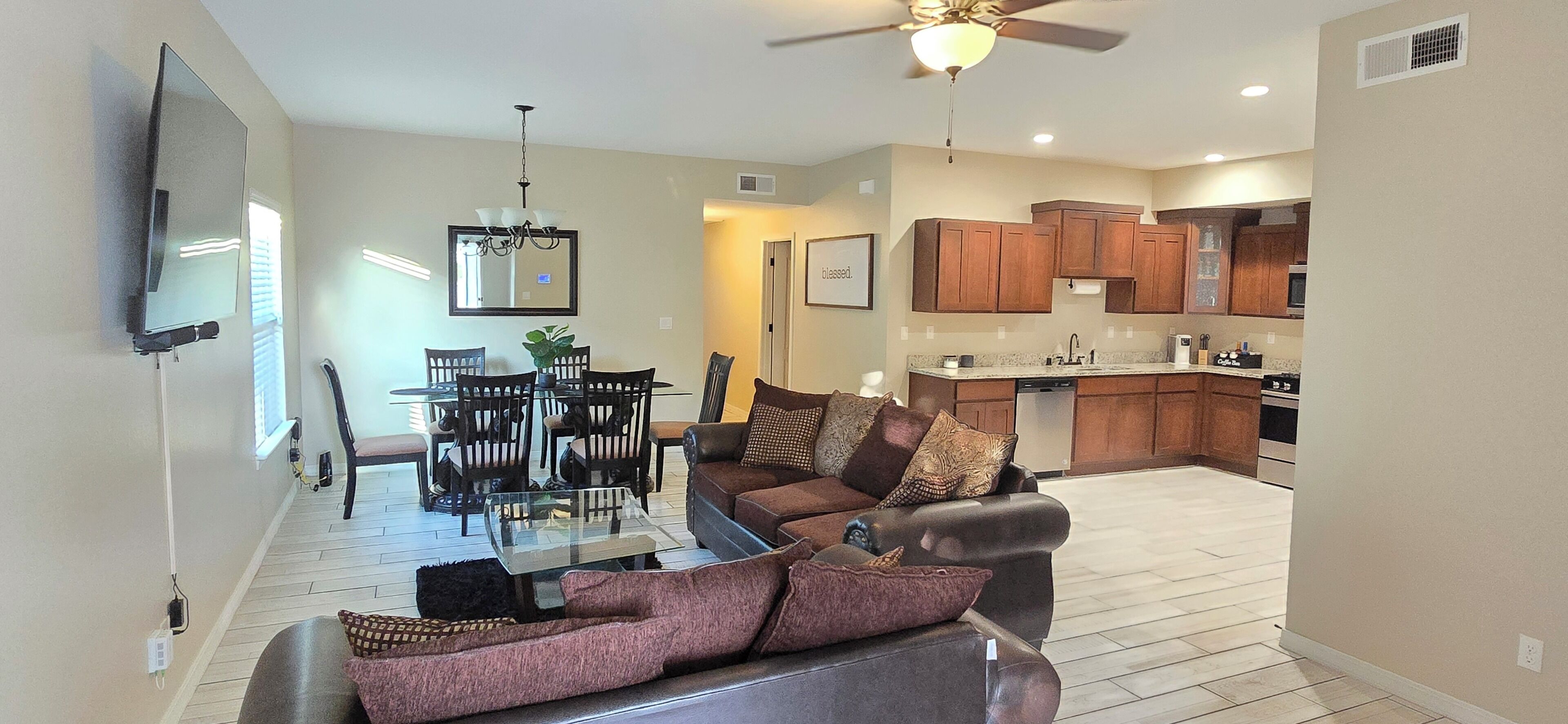 A modern living room with a glass coffee table, a sofa, and a dining area with chairs and a table.