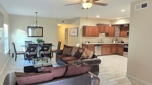A modern living room with a glass coffee table, a sofa, and a dining area with chairs and a table.