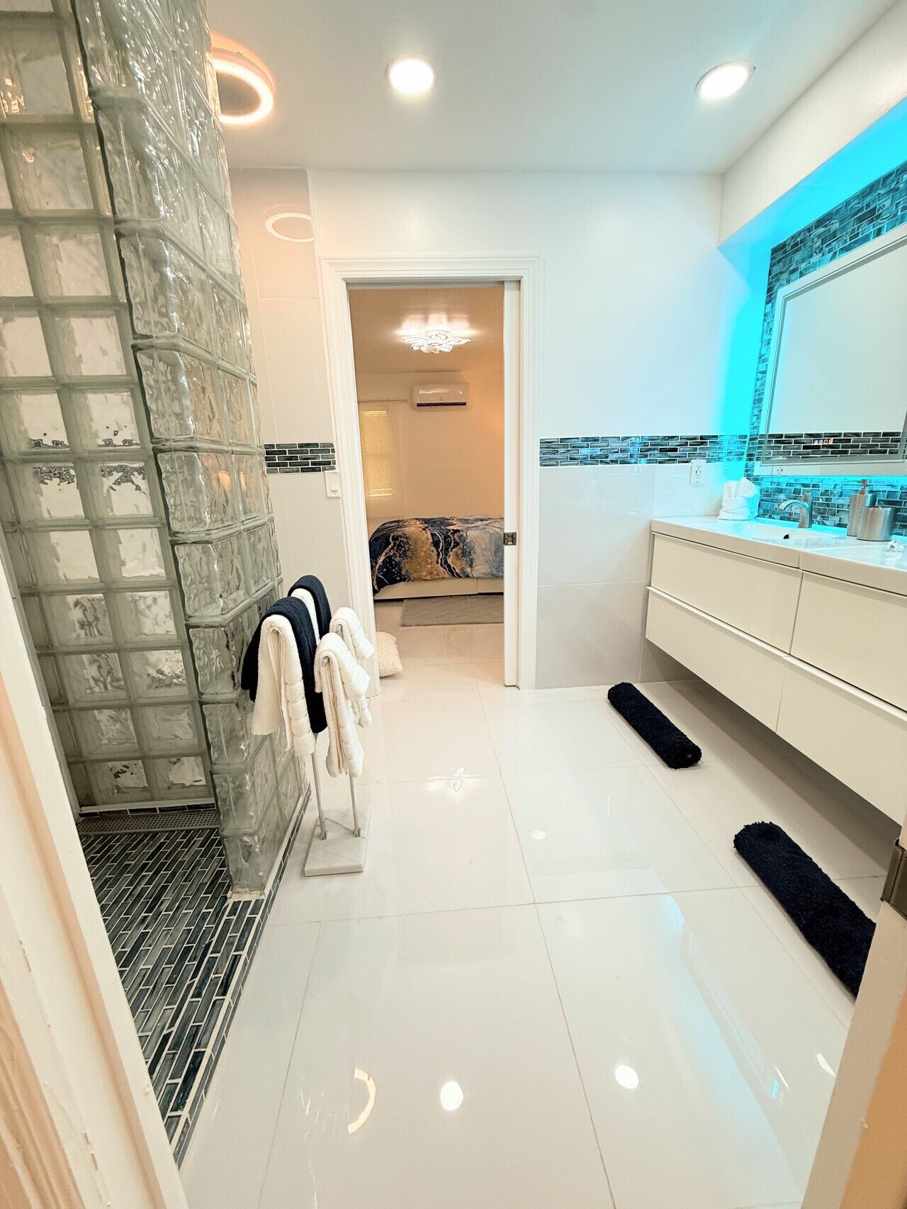 A modern bathroom with a glass shower enclosure, a white vanity with a mirror, and a tiled floor.