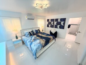 A modern bedroom with a large bed, bedside tables, a ceiling light, and abstract wall art. - Short Walk to Beach • 3BR Poolside Unit • Next to Nature Preserve (Fort Myers Beach)
