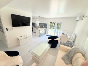 A modern living room with a flat-screen TV, a glass coffee table, and a sofa. - Short Walk to Beach • 3BR Poolside Unit • Next to Nature Preserve (Fort Myers Beach)