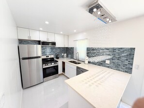 A modern kitchen with stainless steel appliances, a tiled backsplash, and a light-colored countertop. - Short Walk to Beach • 3BR Poolside Unit • Next to Nature Preserve (Fort Myers Beach)