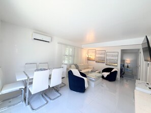 A modern living room with a dining area, a sofa set, and a flat-screen TV. - Short Walk to Beach • 3BR Poolside Unit • Next to Nature Preserve (Fort Myers Beach)
