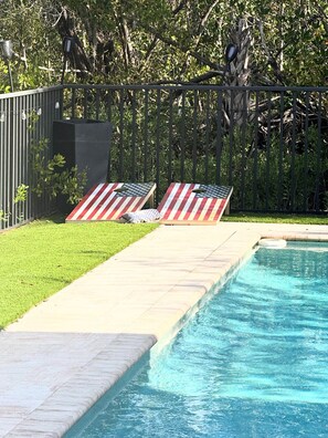A swimming pool with two lounge chairs, a grassy area, and a metal fence. - Big Groups,Nature View Estates 3 units private pool, WALK TO BEACH (Fort Myers Beach)